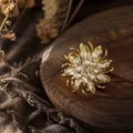 Detail view of an elegant flower brooch with sparkling crystals on a wooden surface - Flower Rhinestone (Gold) / Gold