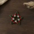 Gedetailleerd overzicht van een kerststerbroche van legering met rode en groene steentjes - Ster Broche