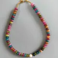 Detail van veelkleurige abacus kralenketting met een centrale witte parel. - Groen, zwart, rood en geel (38+5 cm)