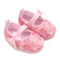 Close-up detail of pink baby Mary Jane shoes featuring 3D floral texture and cute bows. - Pink