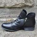 Detailed side view of black leather ankle boots featuring pleated texture and side zipper. - 35 / Black