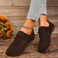 Κομψά γυναικεία καφέ σουέτ δετά φλατ παπούτσια σε ρουστίκ ξύλινο περιβάλλον. - Καφέ
