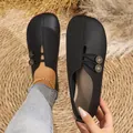 Detailed view of women's black soft leather slip-on flats with decorative buttons - Solid Black