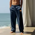 Man wearing navy blue loose-fitting drawstring linen beach trousers on a sunny balcony - S / Bottoms / Navy Blue