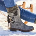 Vista lateral detallada de las botas de nieve grises vintage con puños de punto sobre la nieve - Gris