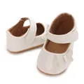 Close-up of white baby girl princess shoes with a delicate bow and Velcro strap. - White