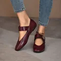 Close-up view of elegant burgundy patent leather Mary Jane flats with buckle strap detail - Burgundy