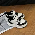 Primo piano di sneaker per bambini bianche e nere con chiusura a strappo e suola spessa - 29 / Nero