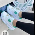 Detailed view of white platform sneakers with green accents and gold lace buckle - Light Green