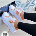 Close-up of stylish white platform sneakers with orange trim and decorative hardware accents - 36 / Orange Red