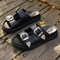 Schwarze Damen-Plateausandalen mit verzierten Silberschnallen auf rustikalem Holzdeck - Schwarz