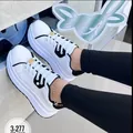 Detailed side view of women's white platform sneakers with black accents worn by model. - 36 / White