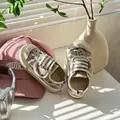 Nahaufnahme von cremefarbenen Kinderschuhen mit Sternenmuster und Klettverschluss - Rot