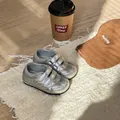 Primo piano di scarpe da bambino argento metallizzato con velcro su un tappeto ruvido - Argento