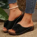 Primer plano de sandalias con cuña negras con elegante aplique de flor y pespuntes - 36 / Negro