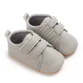 Détail de chaussures de marche pour bébé en gris avec doubles brides velcro et semelles. - Gris