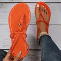 Primo piano di sandali infradito piatti arancione vivace con cinturini sottili in estate. - 36 / arancio-rosso