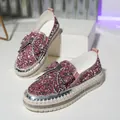 Detail view of pink rhinestone loafers featuring a large sparkly bow and thick platform sole - Pink