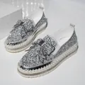 Detailed view of silver rhinestone platform loafers featuring a decorative bow on the toe. - Silver