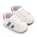 Primo piano di scarpe primi passi bianche per neonati con dettagli in pelle blu e arancione - Bordo Blu