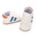 Macro view of white baby walking shoes with blue stripes and soft anti-slip soles - White Blue