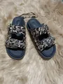 Detalle de sandalias de leopardo con hebillas metálicas decoradas y tachuelas en alfombra de piel. - Estampado de leopardo