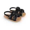 Detail view of black ruffled leather baby sandals with soft tan soles for infant girls - 11cm / Black