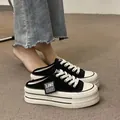 Close-up of black platform mule sneakers with thick white soles and canvas upper. - 35 / Black