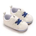 Close-up of white newborn baby boy walking shoes featuring blue laces and a soft sole. - White