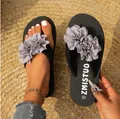 Vue détaillée de tongs plates d'été ornées d'élégantes fleurs en tissu gris. - Gris
