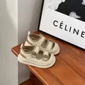 Detailed close-up view of cream baby sandals with double straps on a wooden surface - Size 16 / Internal Length 12.5cm / Beige
