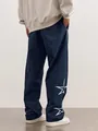 Detailed view of men's navy track pants with white star embroidery on the lower leg. - Navy Blue