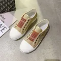 Detailed top view of tan canvas sneakers featuring colorful striped elastic bands. - 35 / Apricot