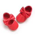 Detail von hellroten Babyschuhen für Mädchen mit großer Schleife und weicher Sohle - Rot