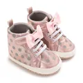 Nahaufnahme von rosa glitzernden Lauflernschuhen mit grauen Punkten und Schleife. - Rosa
