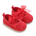 Nahaufnahme von roten Babyschuhen mit großer Schleife und feiner Blumenstickerei - Rot