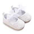 Detailansicht weißer Babyschuhe aus Spitze mit dekorativer Seidenschleife und Stickerei. - Weiß
