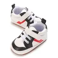 Λεπτομερής όψη λευκών και μαύρων βρεφικών παπουτσιών με κόκκινες διακοσμητικές ρίγες - Λευκό Μαύρο