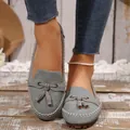Grijze suède-look loafers voor dames met kwastjesstrik op een rustieke houten vloer - 36 / Grijs