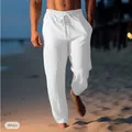 Detail view of men's white linen beach trousers with drawstring waist on a sandy beach - White