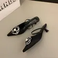 Mules élégantes à bout pointu noir avec ornement camélia en perle blanche. - Noir
