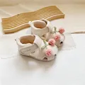 Primer plano de sandalias para bebés con flores de pompones rosas y lazos verdes - Blanco Roto
