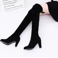 Detail showing the sleek fit of black suede over-the-knee high-heel boots on legs. - 37 / Black
