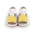 Detail view of white baby walking sandals with yellow shell decoration and velcro strap. - Yellow