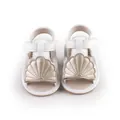 Detailed front view of white baby sandals with gold shell accent for pre-walkers. - Gold
