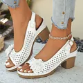 Close-up detail of white hollow-out flower sandals with block heels for elegant summer style. - White
