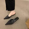 Nahaufnahme der schwarzen spitzen Satin-Mules mit elegantem Pfennigabsatz - Schwarz