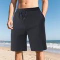 Detail view of men's black jacquard beach shorts with drawstring waist on sunny beach - Black