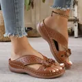 Detailed view of brown wedge sandals featuring hollowed-out patterns and flower accents - Tan