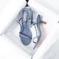 Detail view of light blue stiletto sandals nestled in white packaging paper - 35 / Blue